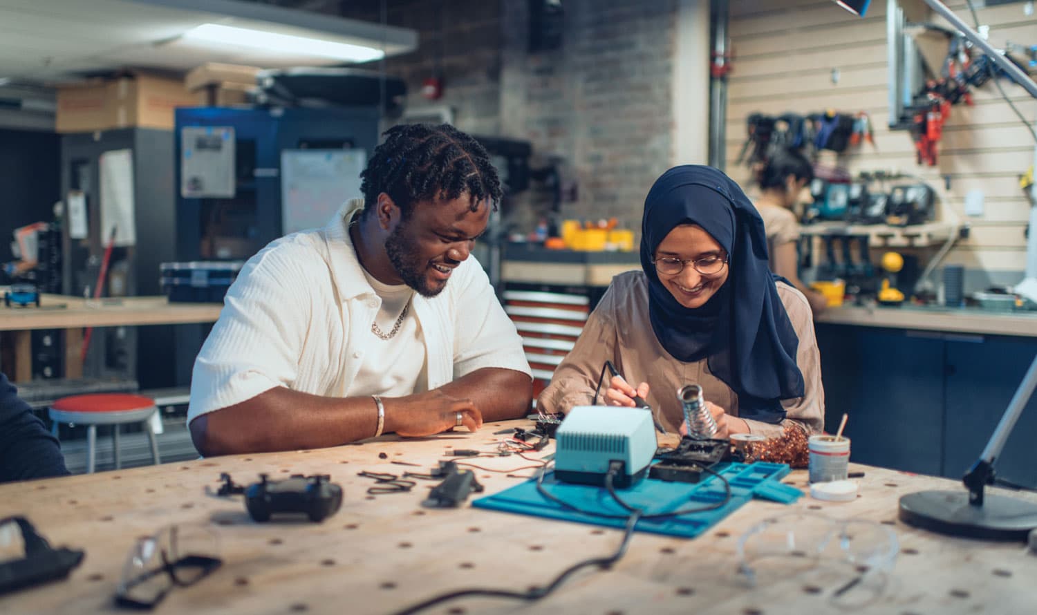 two students in a workshop working on electronics