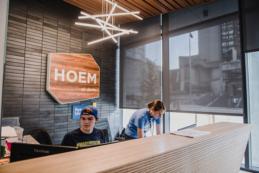 Two people work at the front desk of HOEM on Jarvis during move-in day.