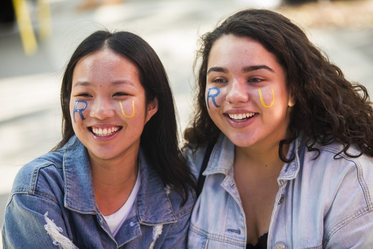 Two students with university colours painted on their face