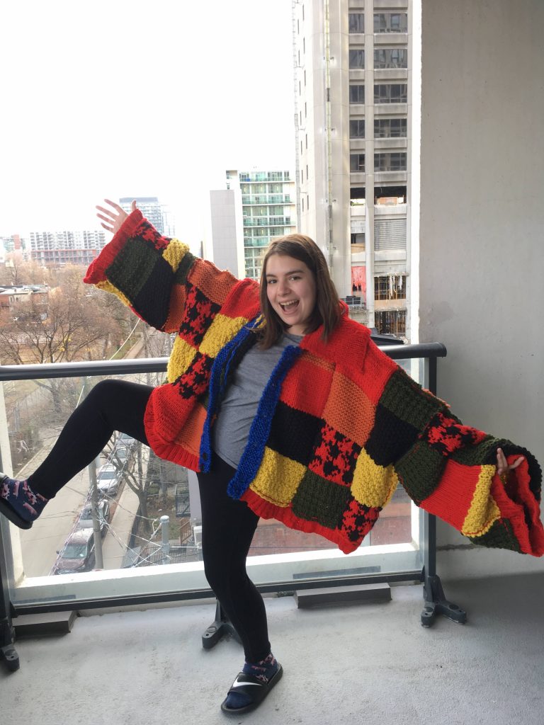 Jenna smiling and posing with a large sweater