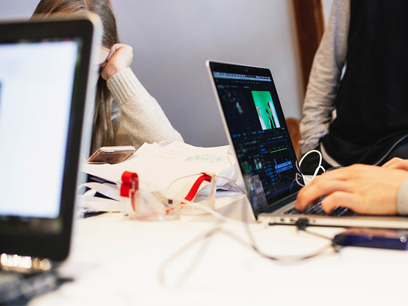 Students at a table work on their laptops