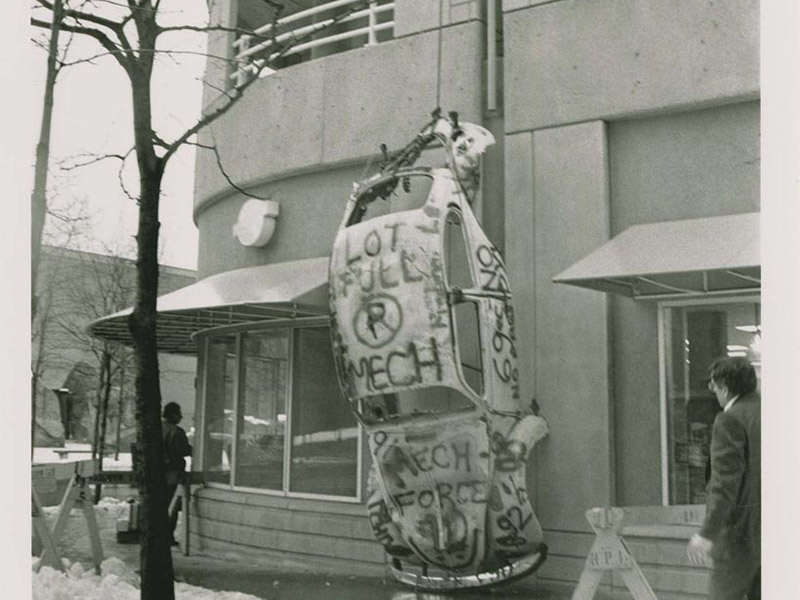 The chassis of a Volkswagen Beetle hangs from the roof of the parking garage