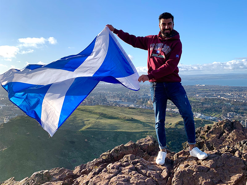 Kashif holds a Scottish flag as it blows in the wind