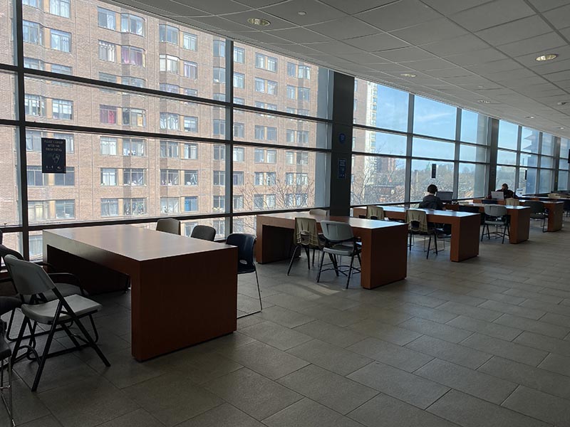 The sun shines on a row of empty tables in front of large floor-to-ceiling windows on the fifth floor of the Sally Horsfall Eaton Centre building.