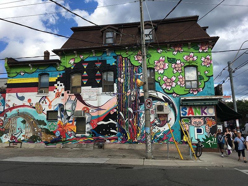 A house with the exterior painted in bright colours and designs in the neighbourhood of West Queen West on a cloudy, fall day.