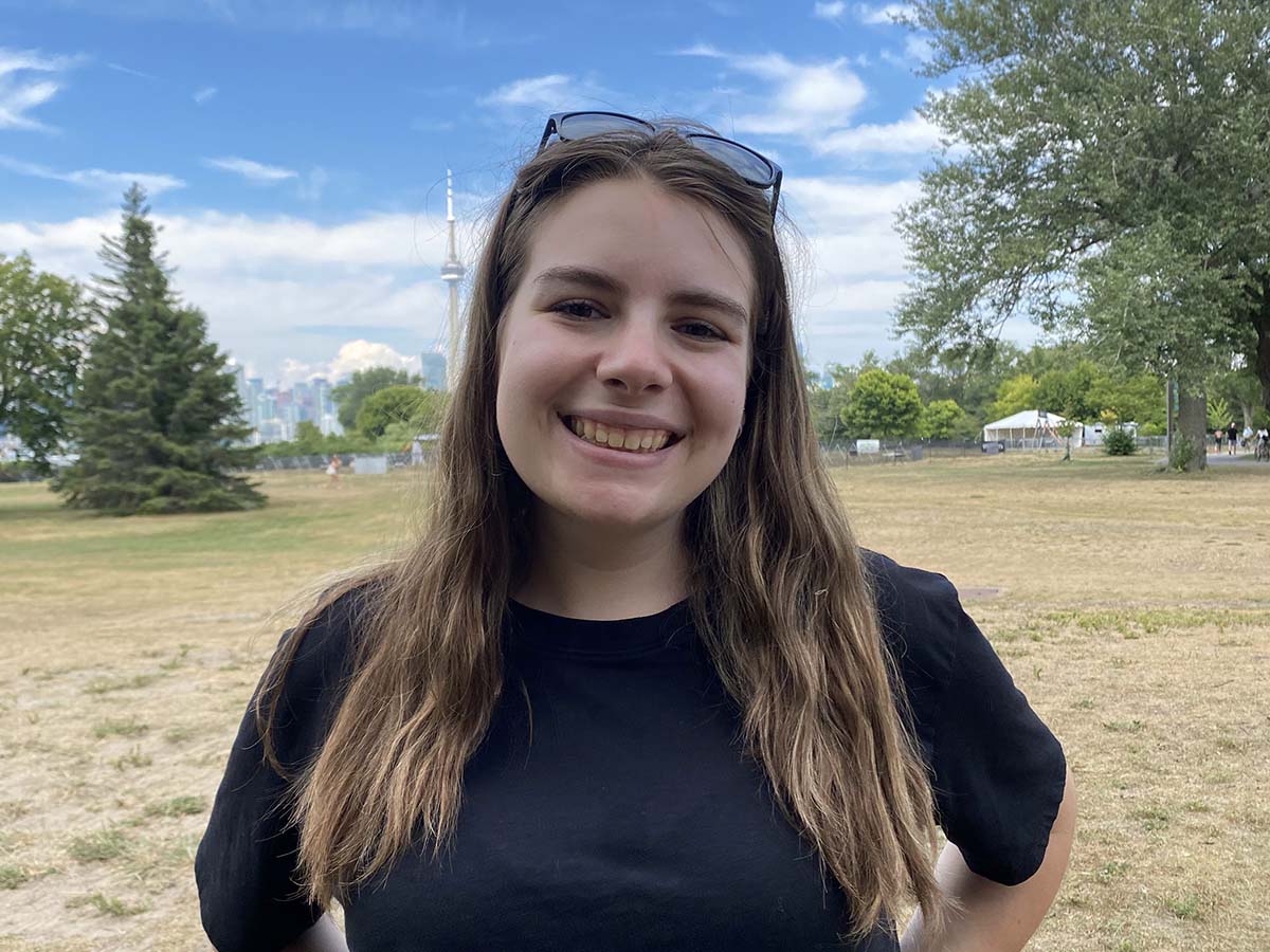 Jenna smiles for a photo with the Toronto skyline in the background while visiting the Toronto Islands. 