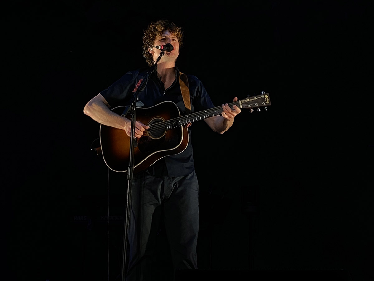 Vance Joy singing with his guitar at his Toronto concert.