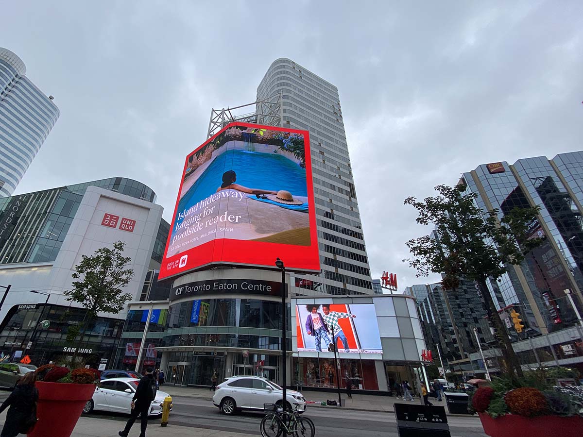 An electronic billboard on top of the CF Toronto Eaton Centre in Yonge-Dundas Square on a cloudy day.