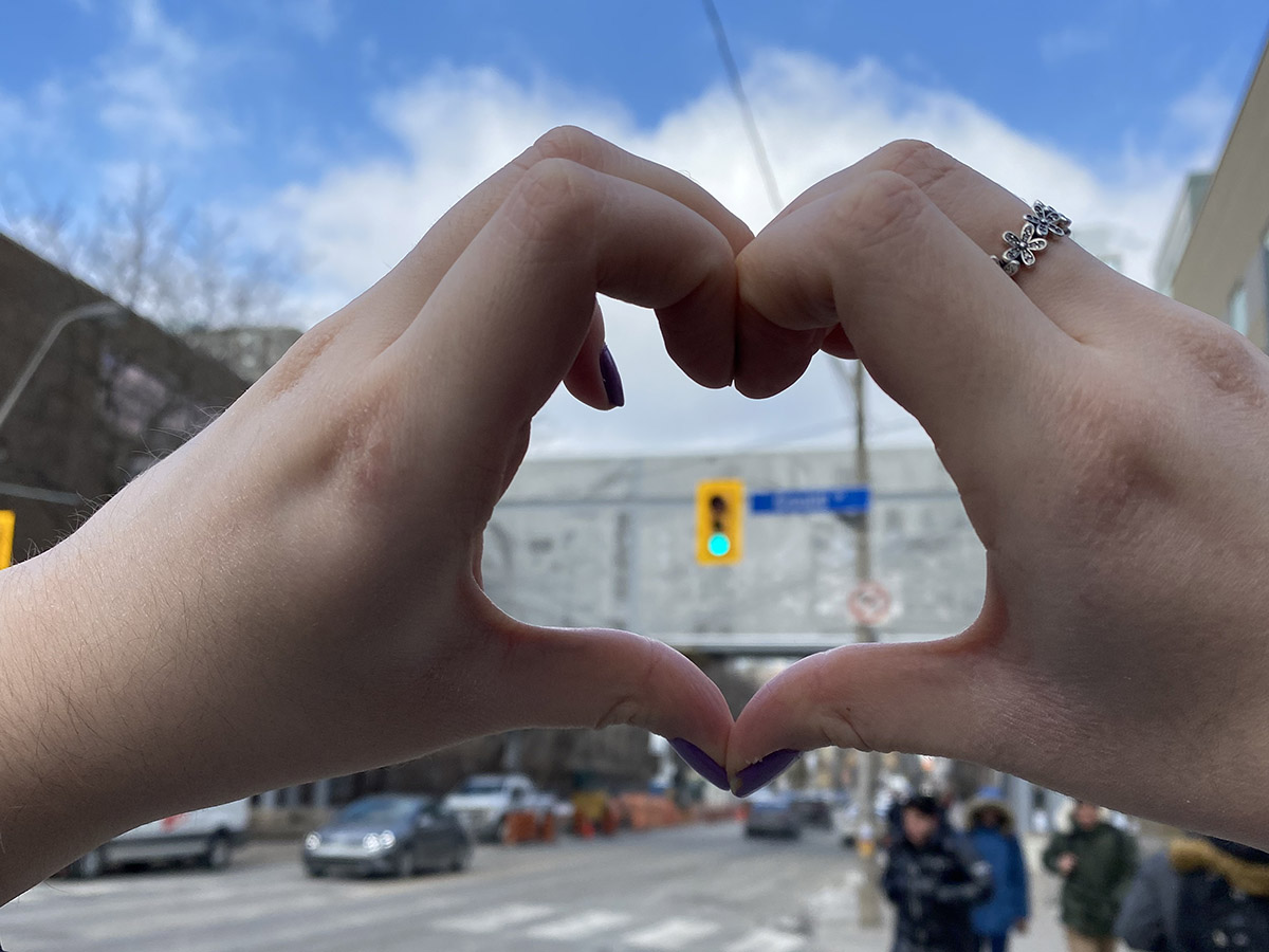 Hands making a heart at the intersection of Church and Gould with the Church Street bridge in the background.