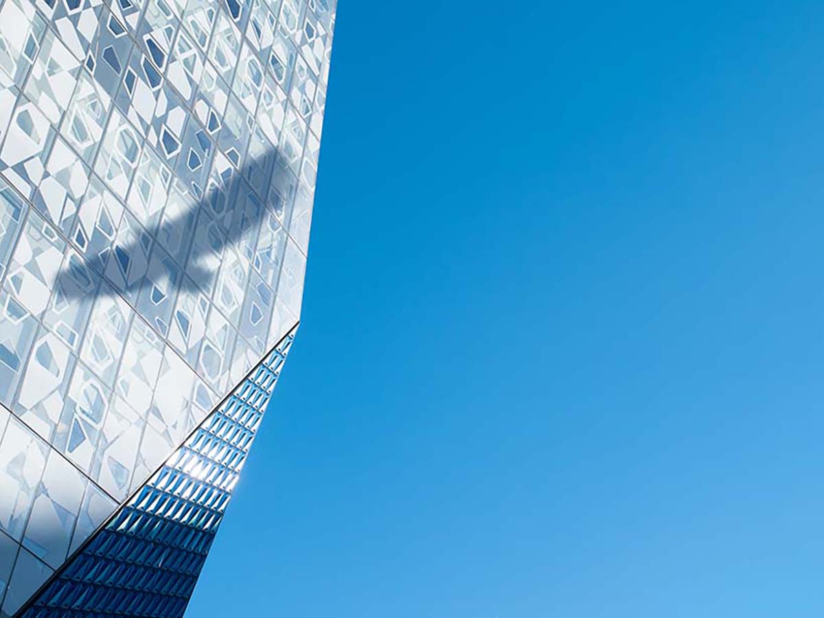 The shadow of a falcon reflects off the exterior of the Student Learning Centre against a bright blue sky.