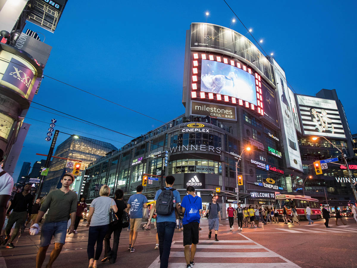 Pedestrians cross the intersection of Yonge and Dundas in the early evening.