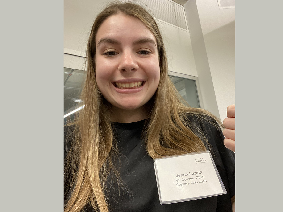 Jenna smiles while wearing a name tag that reads "Jenna Larkin, VP Comms, CICU Creative Industries."