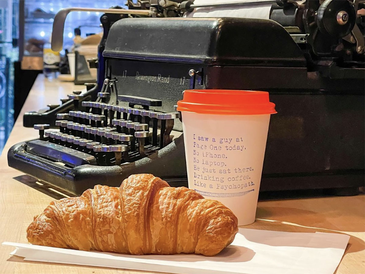 A coffee and a croissant in front of a typewriter at Page One.