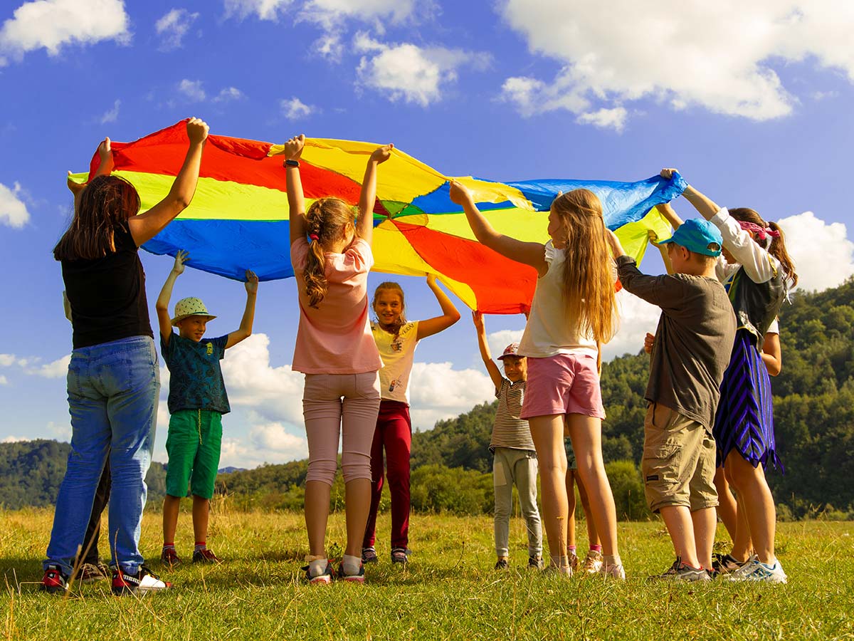 Children playing with a parachute outside in a field.