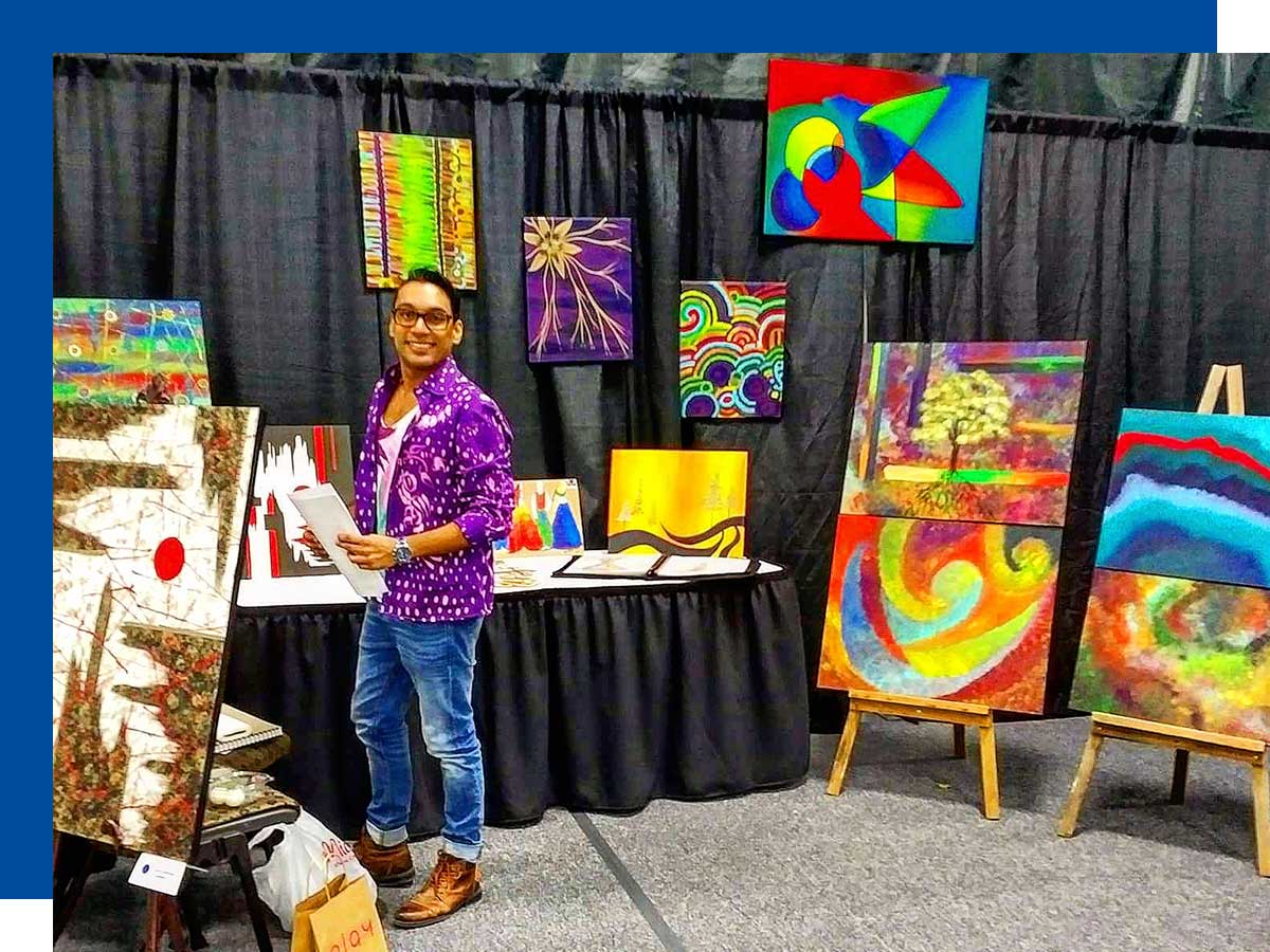 Narishdath stands in front of his abstract paintings