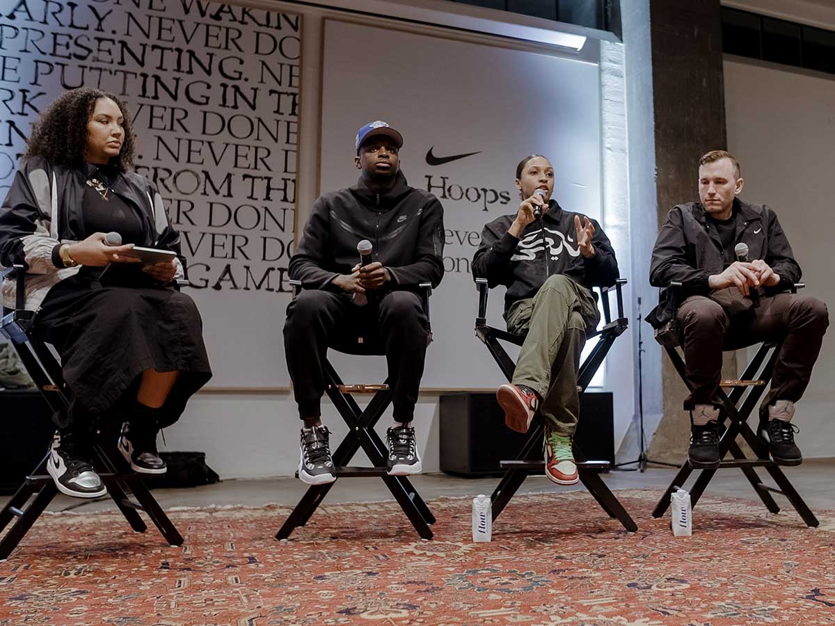  Dakota Whyte speaks into a microphone while seated alongside other panelists at a Nike event.