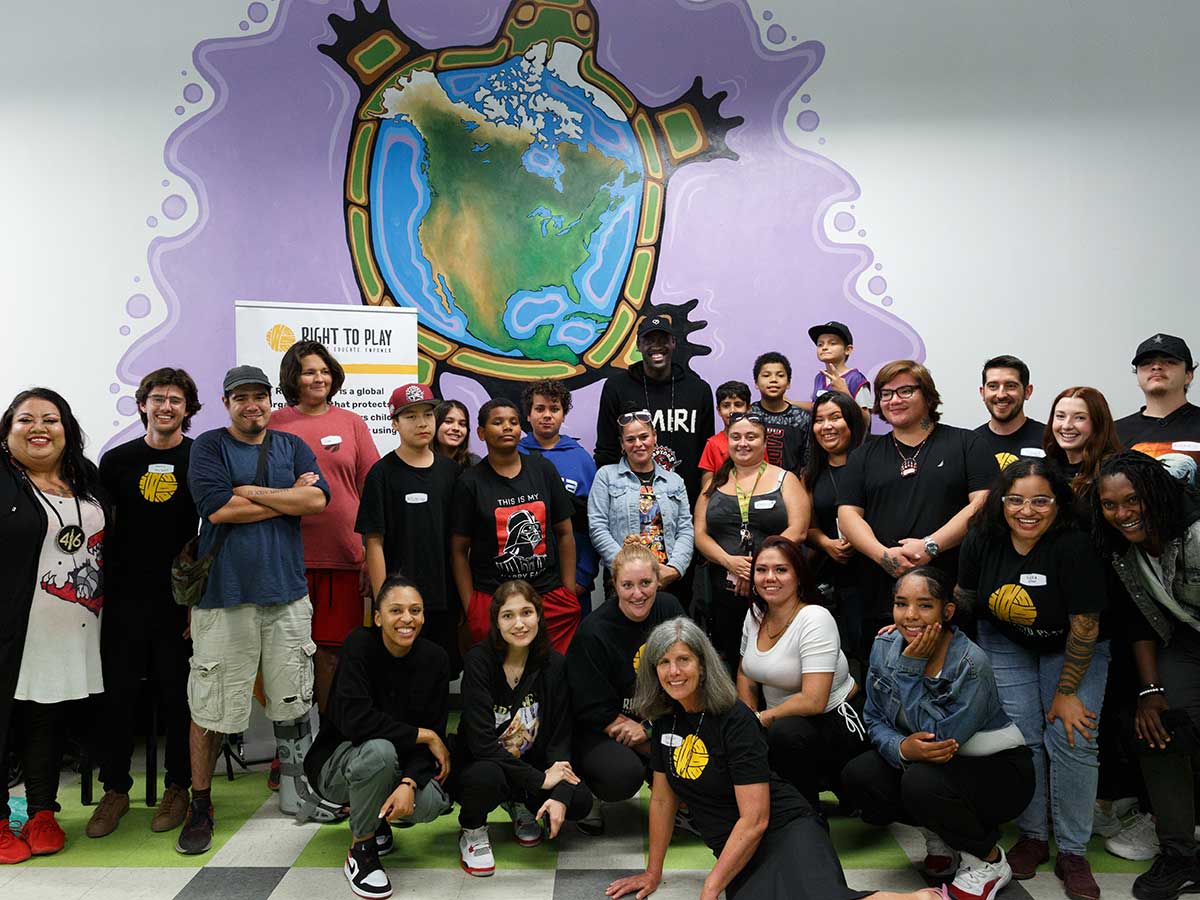 Dakota Whyte and a group of youth and adults pose at an event with former Raptors player Pascal Siakam