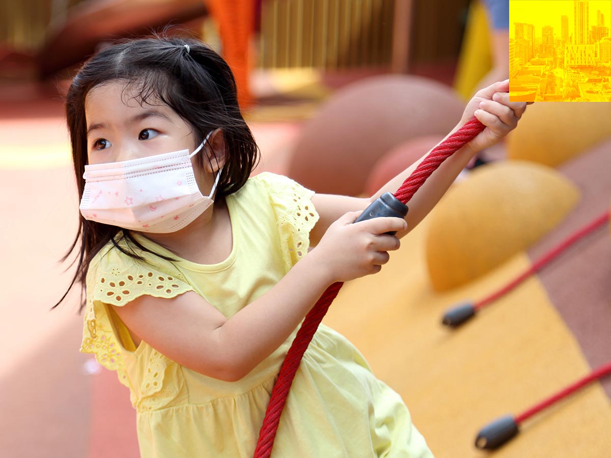 Child with face mask on a play structure