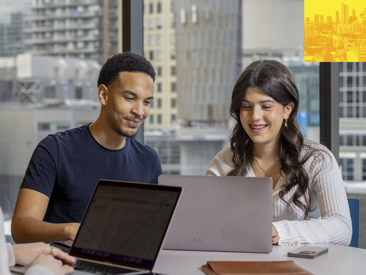 Two people in discussion at a table with a laptop computer