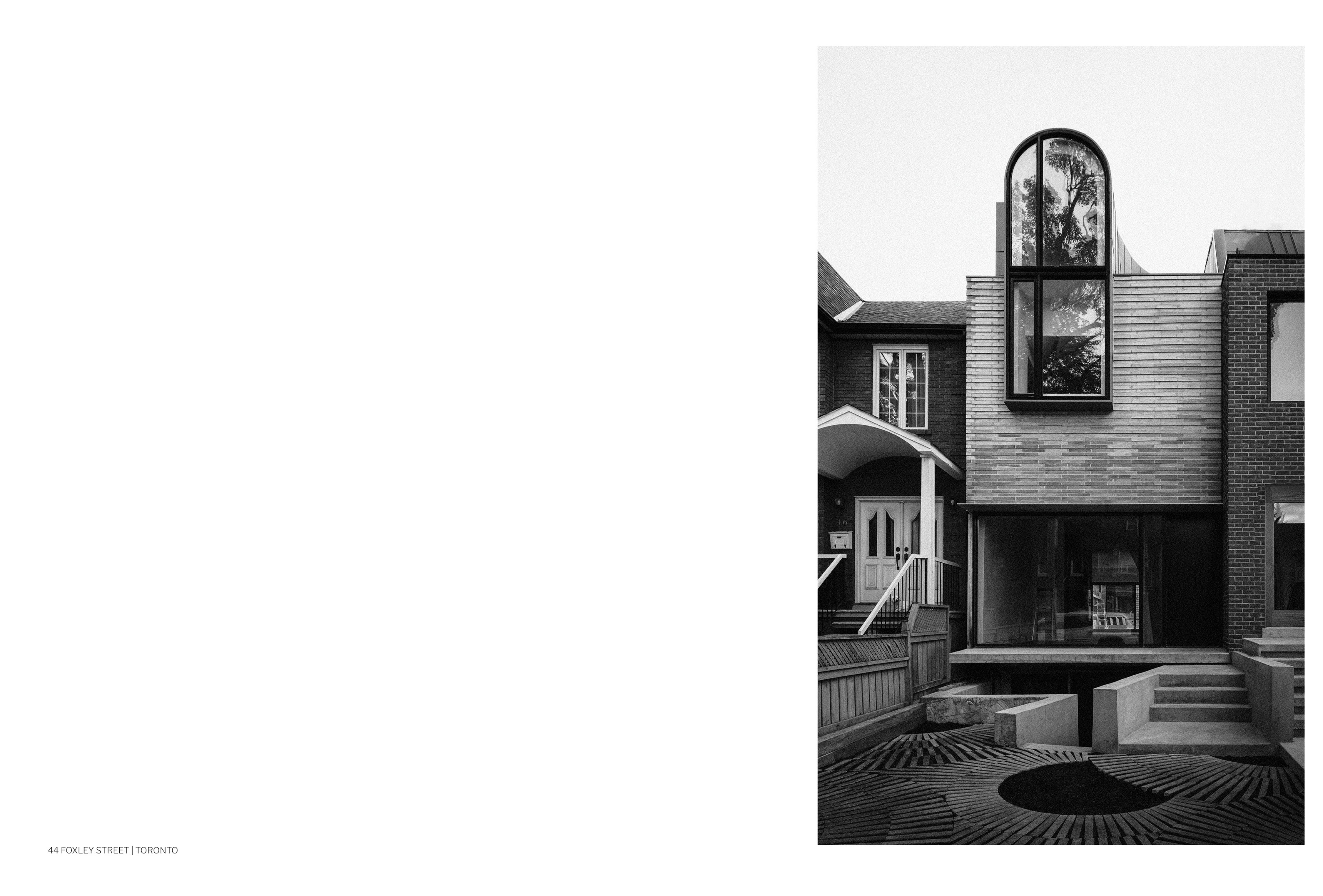 Black and white photo of a renovated home located at 44 Foxley Street, Toronto. A modern home with a protruding window faces a courtyard. Courtesy of Ja Architecture Studio.