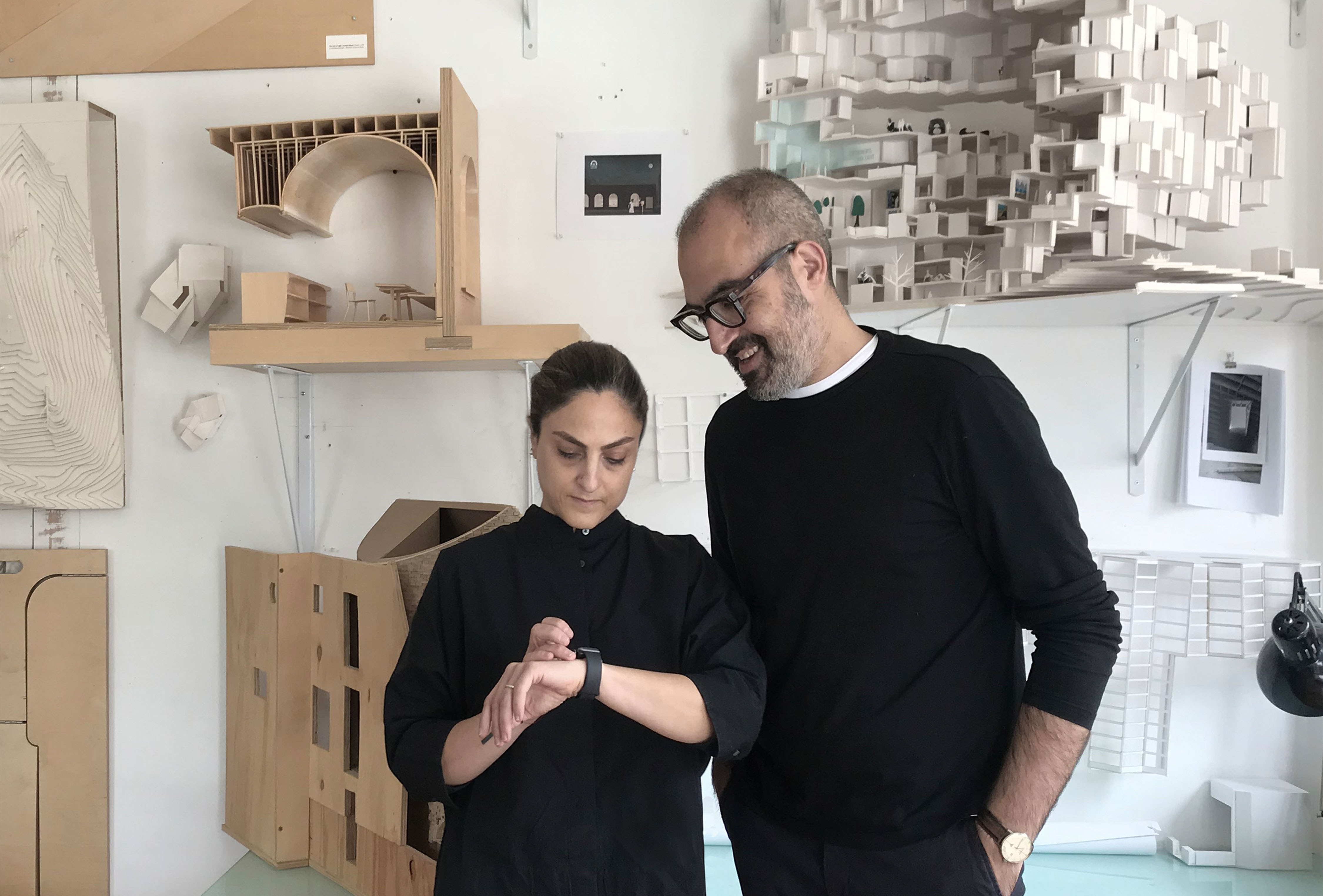 Behnaz Assadi and Nima Javadi looking down and smiling. 