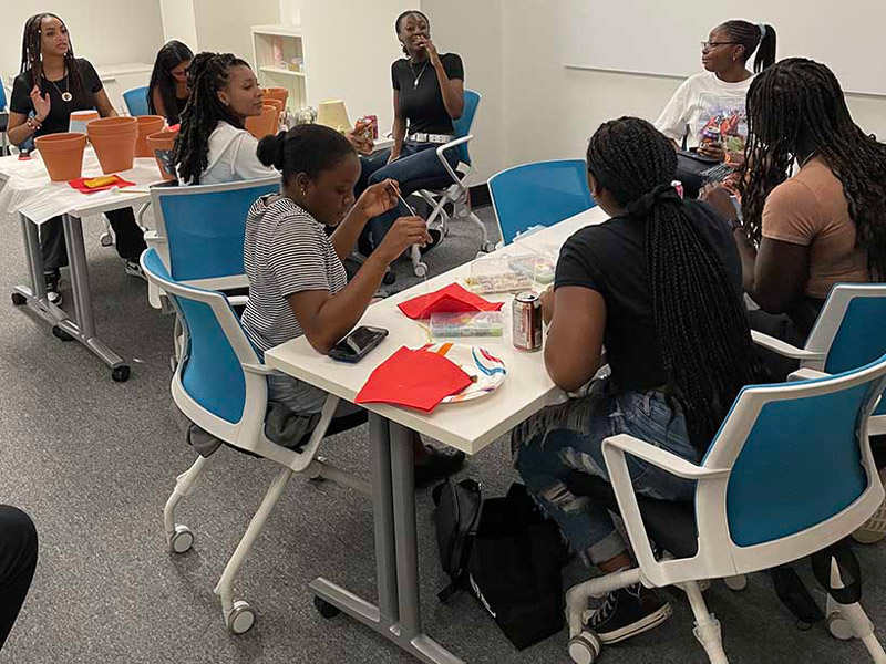 Students in the Black Student Lounge laugh and talk while gathered around tables.