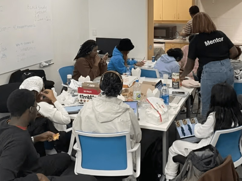 Students eat snacks around the tables in the Black Student Lounge.