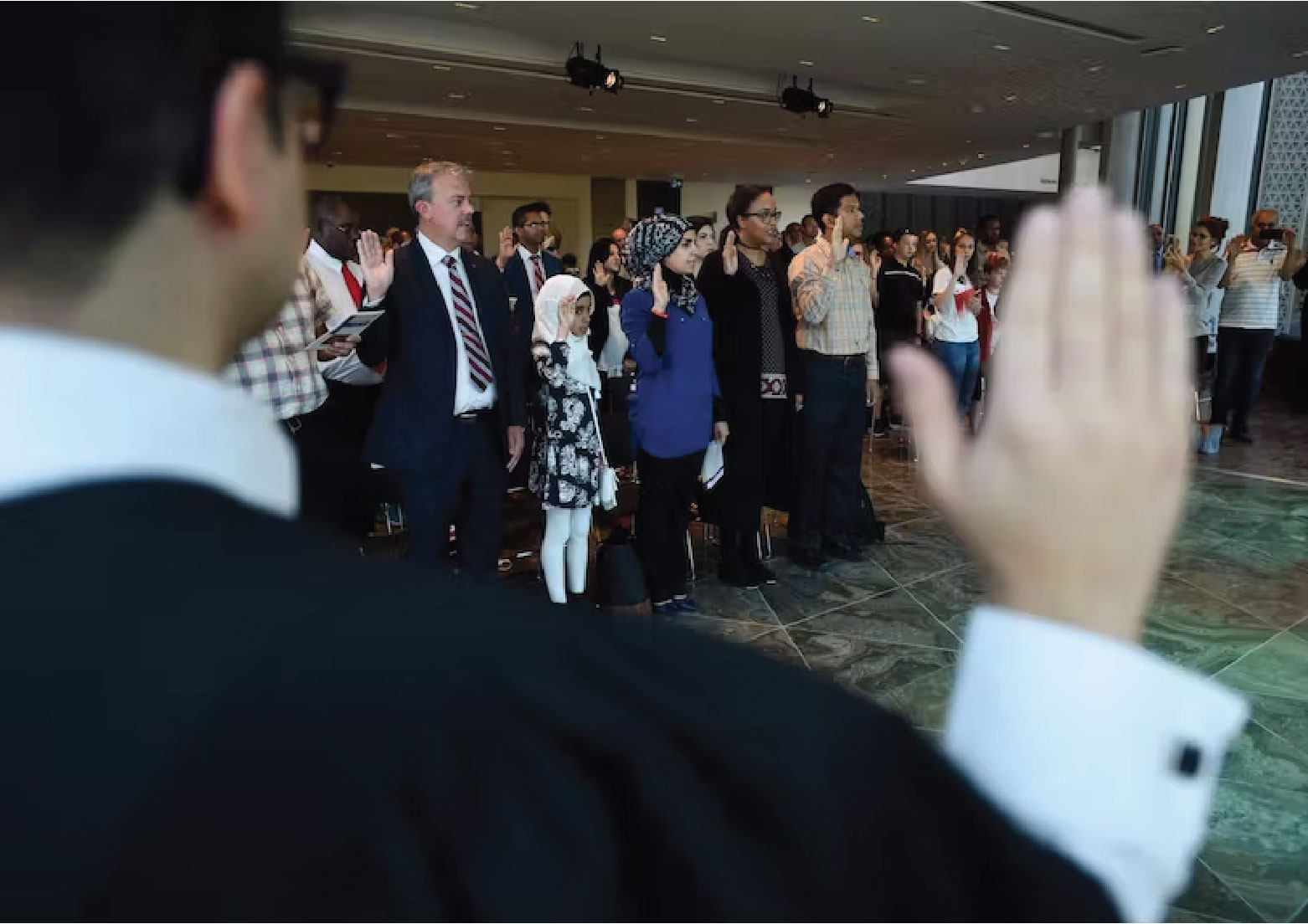 People take the citizenship oath during a ceremony at the National Arts Centre in Ottawa. THE CANADIAN PRESS/Sean Kilpatrick