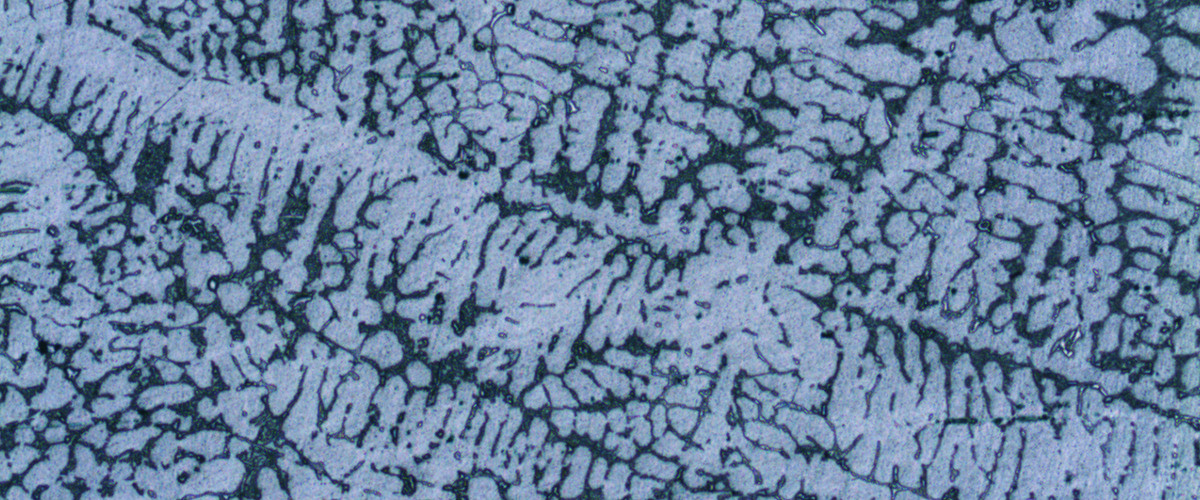 Microscopic close-up of polished aluminum alloy showing dendritic microstructure