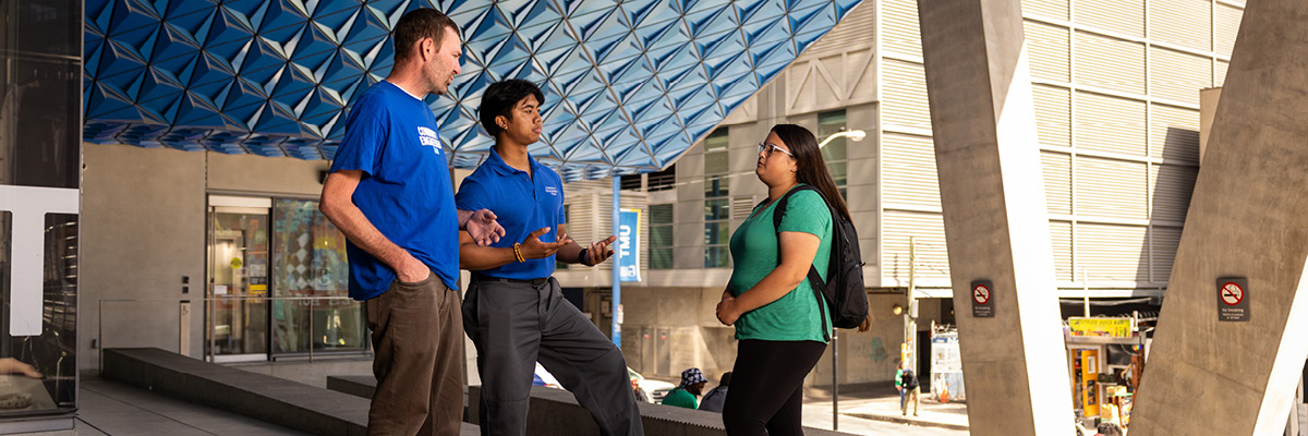 Members of the Community Engagement Team chat with a student on the steps of the SLC.