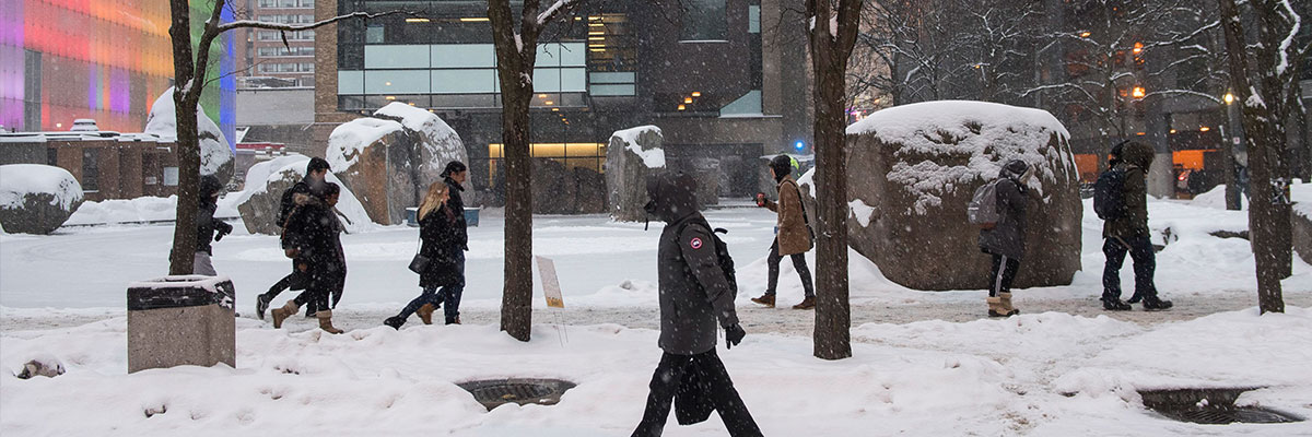 Students walking in front of Lake Devo on a snowy day.