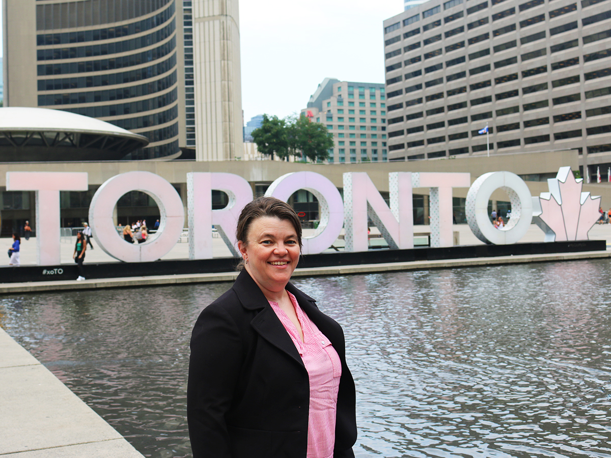 Catherine Cook standing in front of the large Toronto sign at City Hall.