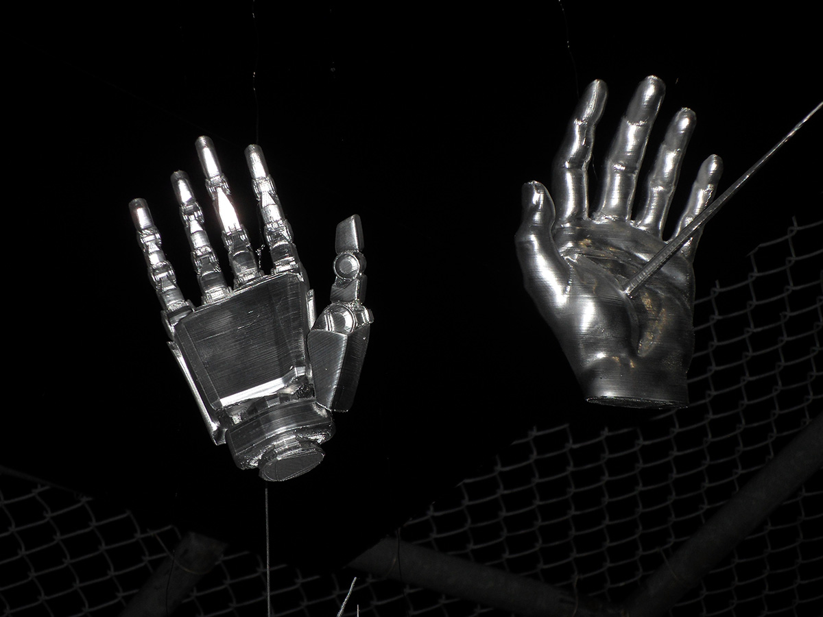 2 metallic hands suspended in a black background.