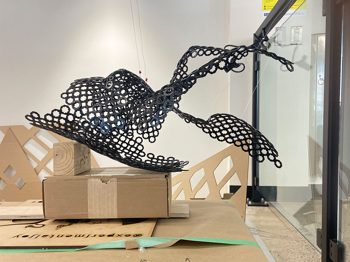 A 3D printed and laser cut sculpture of a portion of a female body rests on a cardboard box in a workspace.