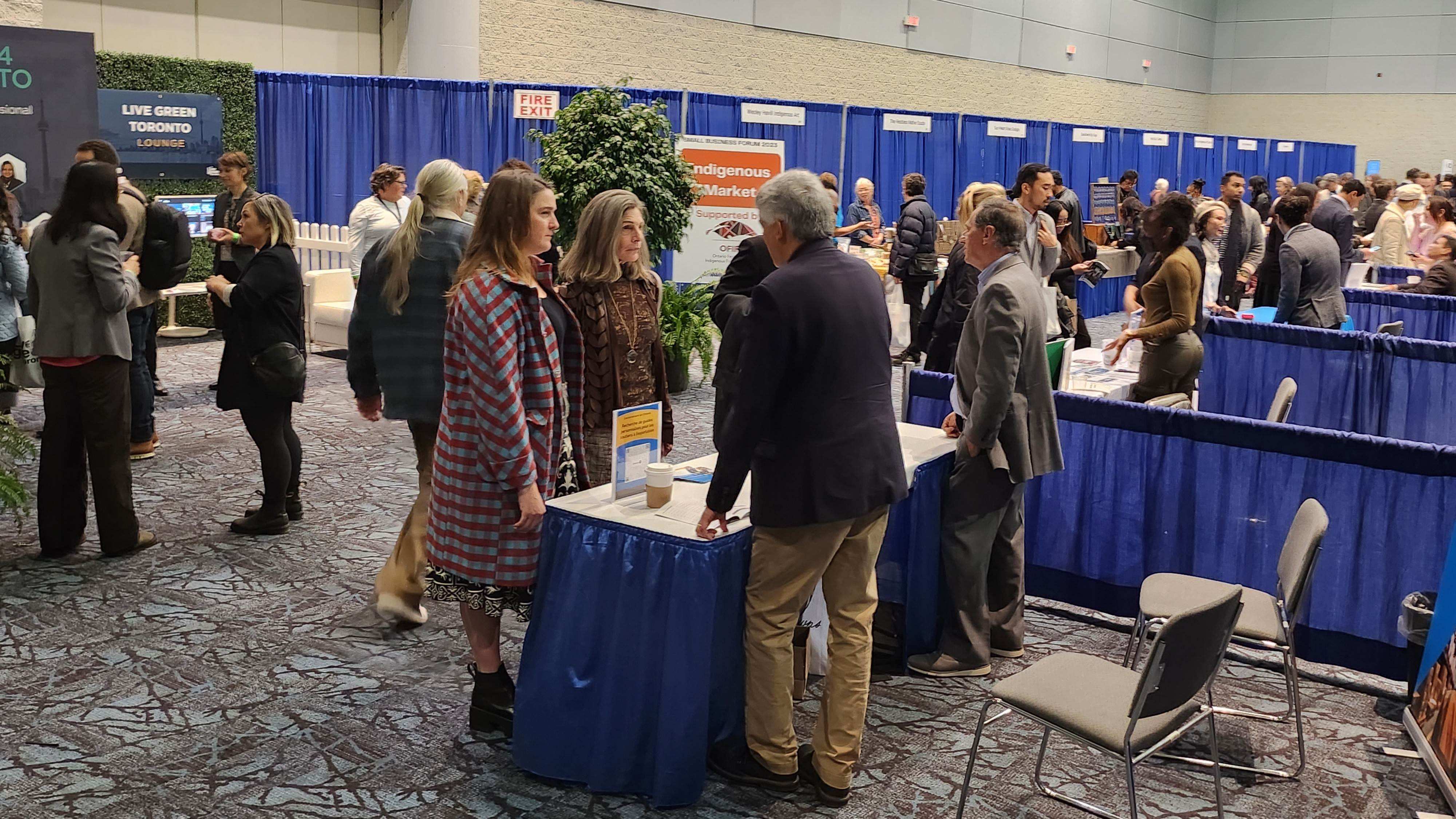 Many people gathered in an exhibition hall with booths representing various businesses and vendors.