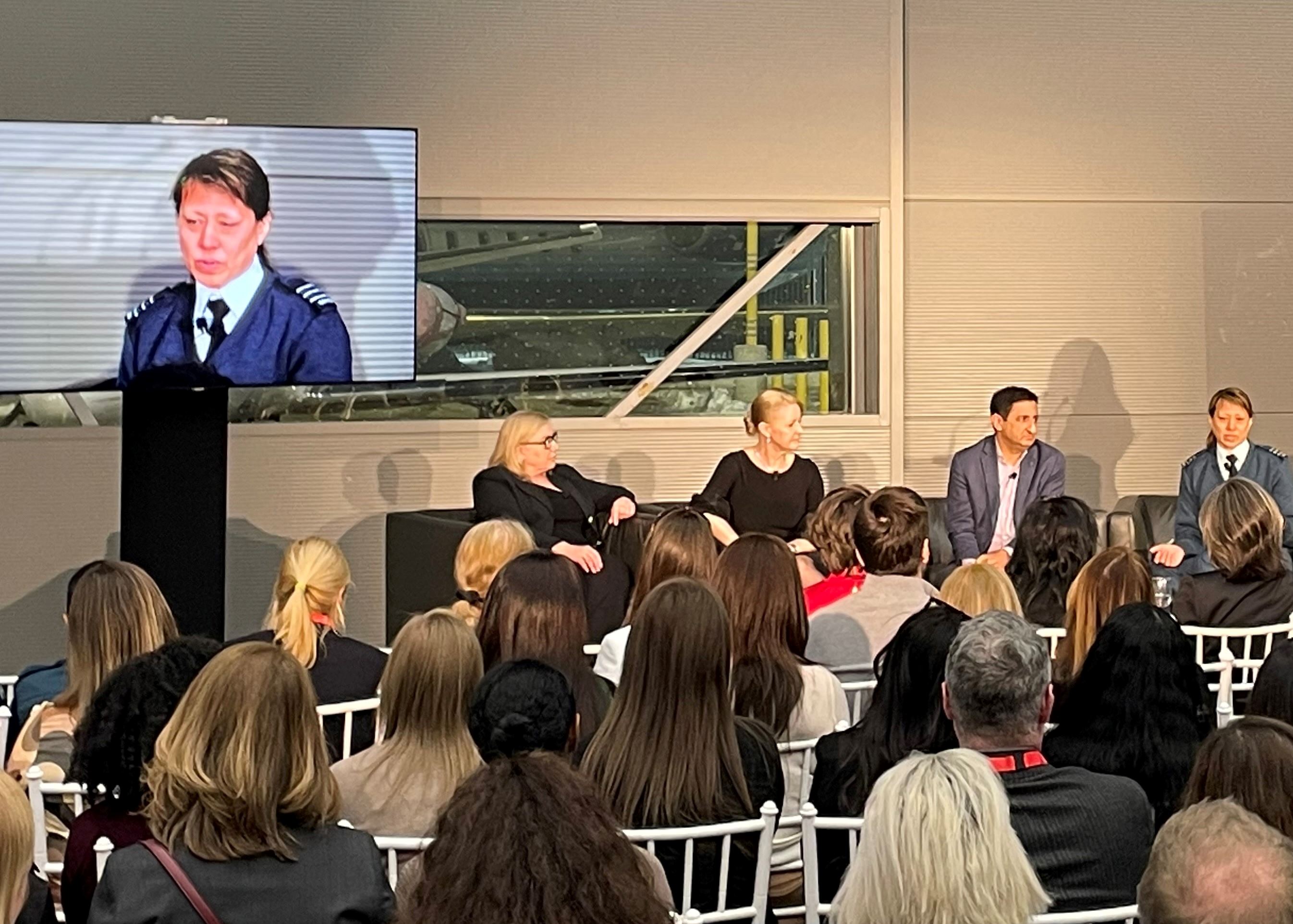 A panel of speakers on a stage at a conference discuss inclusion.