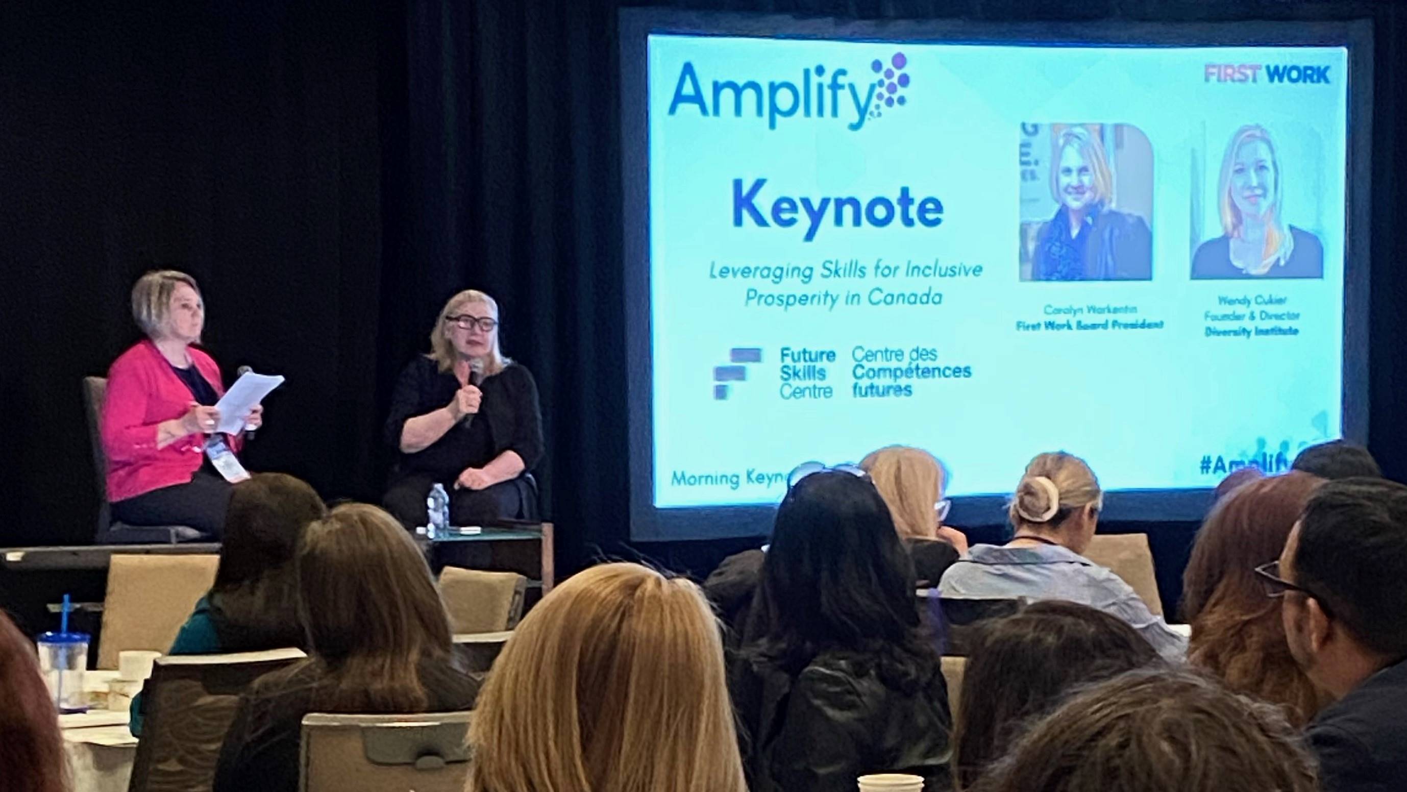 Carolyn Warkentin and Wendy Cukier present a keynote panel to a large seated crowd.