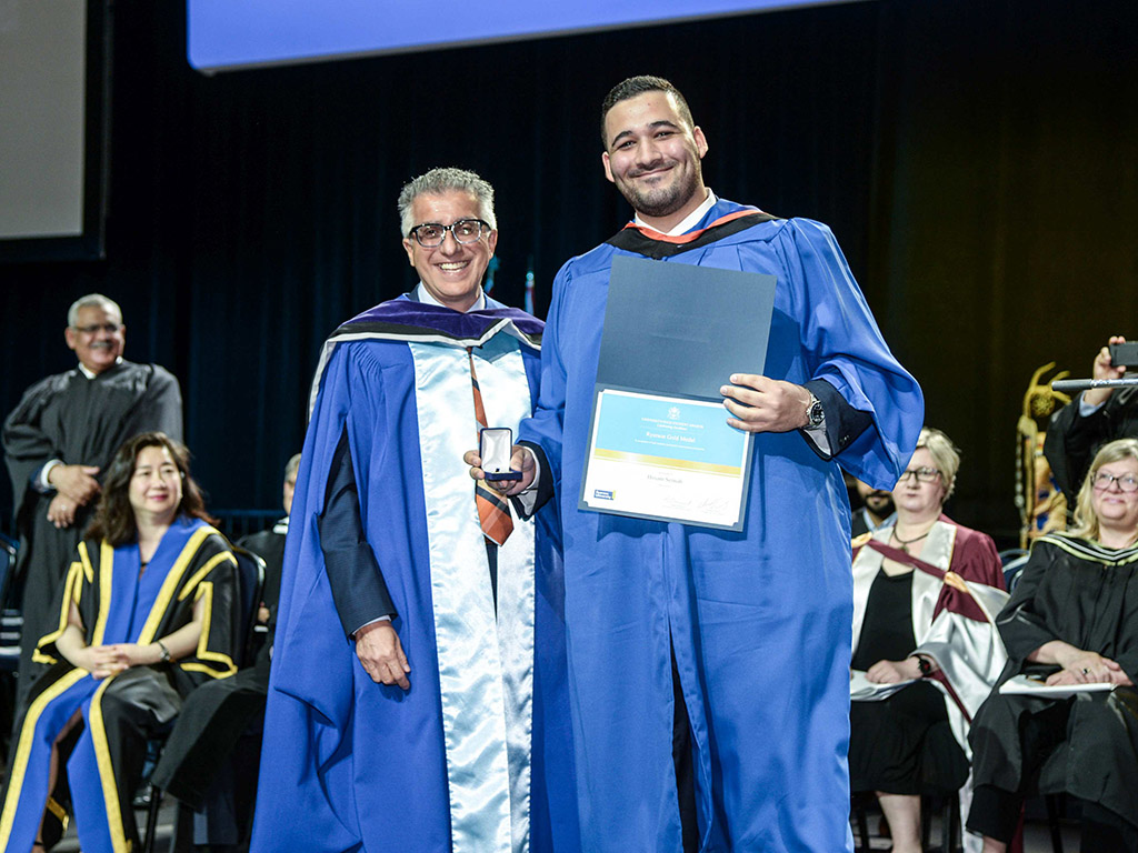 Steven N. Liss and Hosam Sennah pose on stage at convocation with Sennah’s award