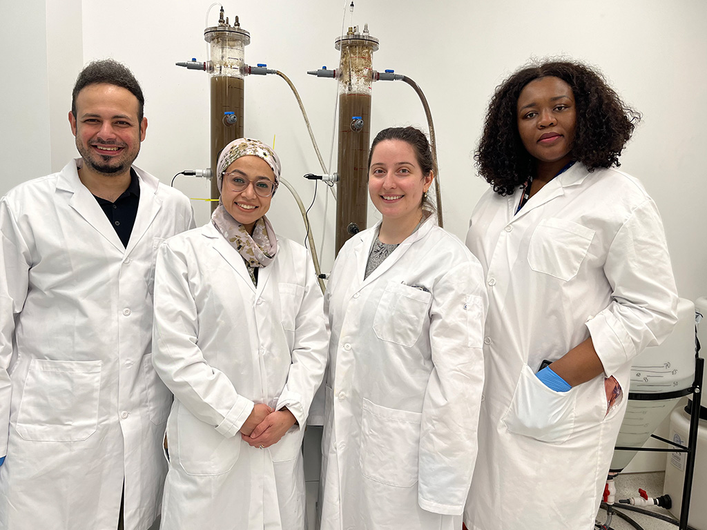 Mohammad Elassar, Rania Hamza, Zanina Ilieva and Victoria Onyed stand together wearing white lab coats looking at the cameraibe