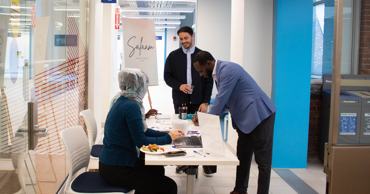 Farhan and Imran talking to a Muslim staff member at an event