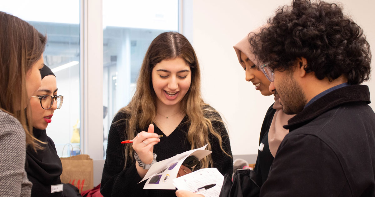 A group of Muslim students, faculty and staff conversing at an event