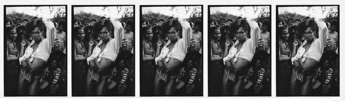 An archival photograph from the 1970s of a Black person in a crop top posing and dancing in the streets at the Gay Liberation March in New York City.