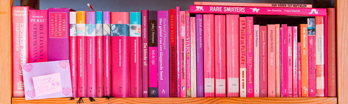 A row of books with pink spines in a library.