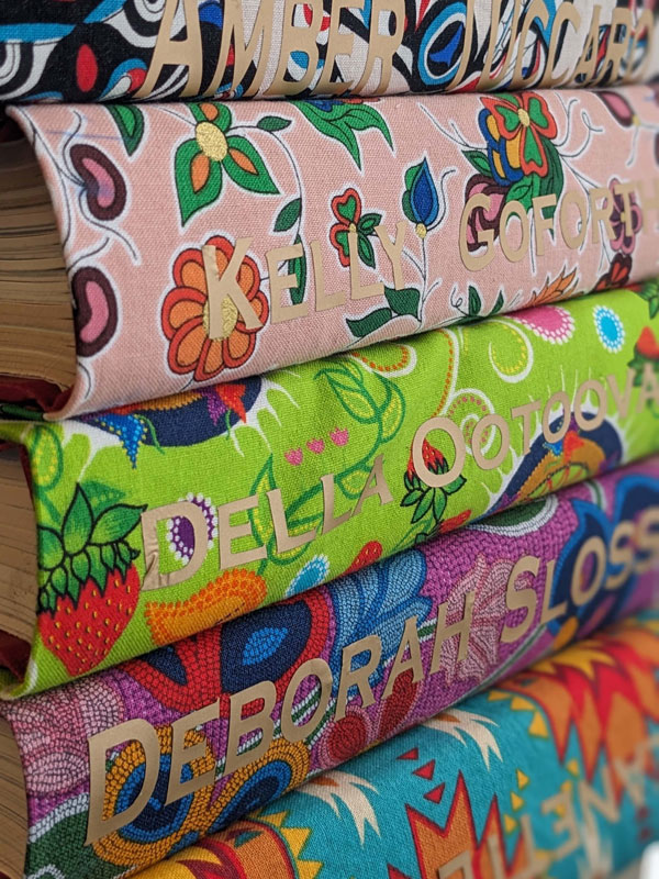 A stack of books bound in colourful and patterned fabric sourced from Indigenous vendors.