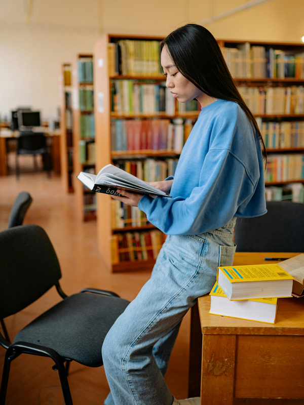 A student reading a book in the TMU Libraries.