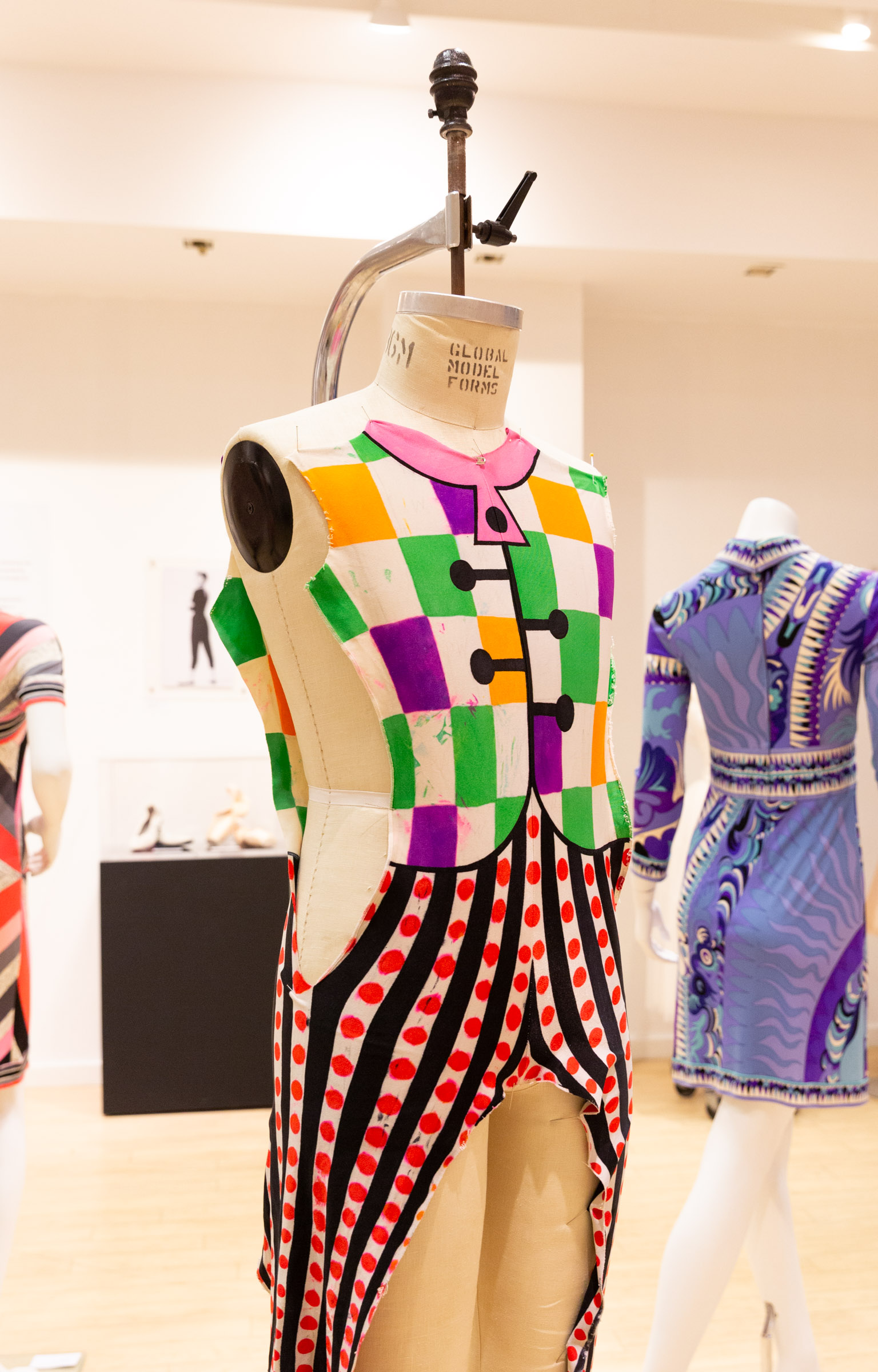 A close up of a purple, green, pink, orange, black and red costume with checkered print on the top, and stripes and polkadots on the bottom. 