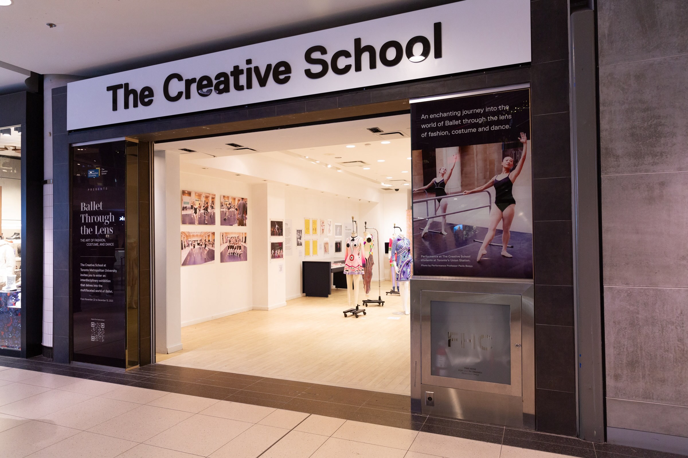 Shows the outside of the exhibit, framed by the sign "The Creative School". 