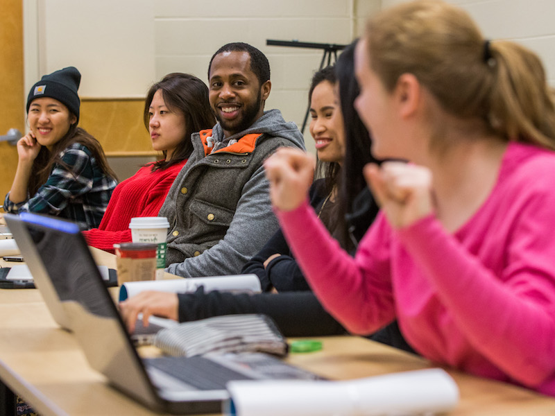 Students looking across a desk at each other while smiling in excitement