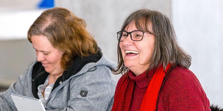 Two seated faculty members smiling