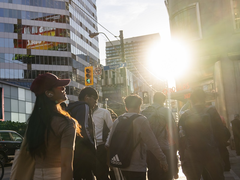 A group of young people walk through the Yonge and Dundas intersection in Toronto